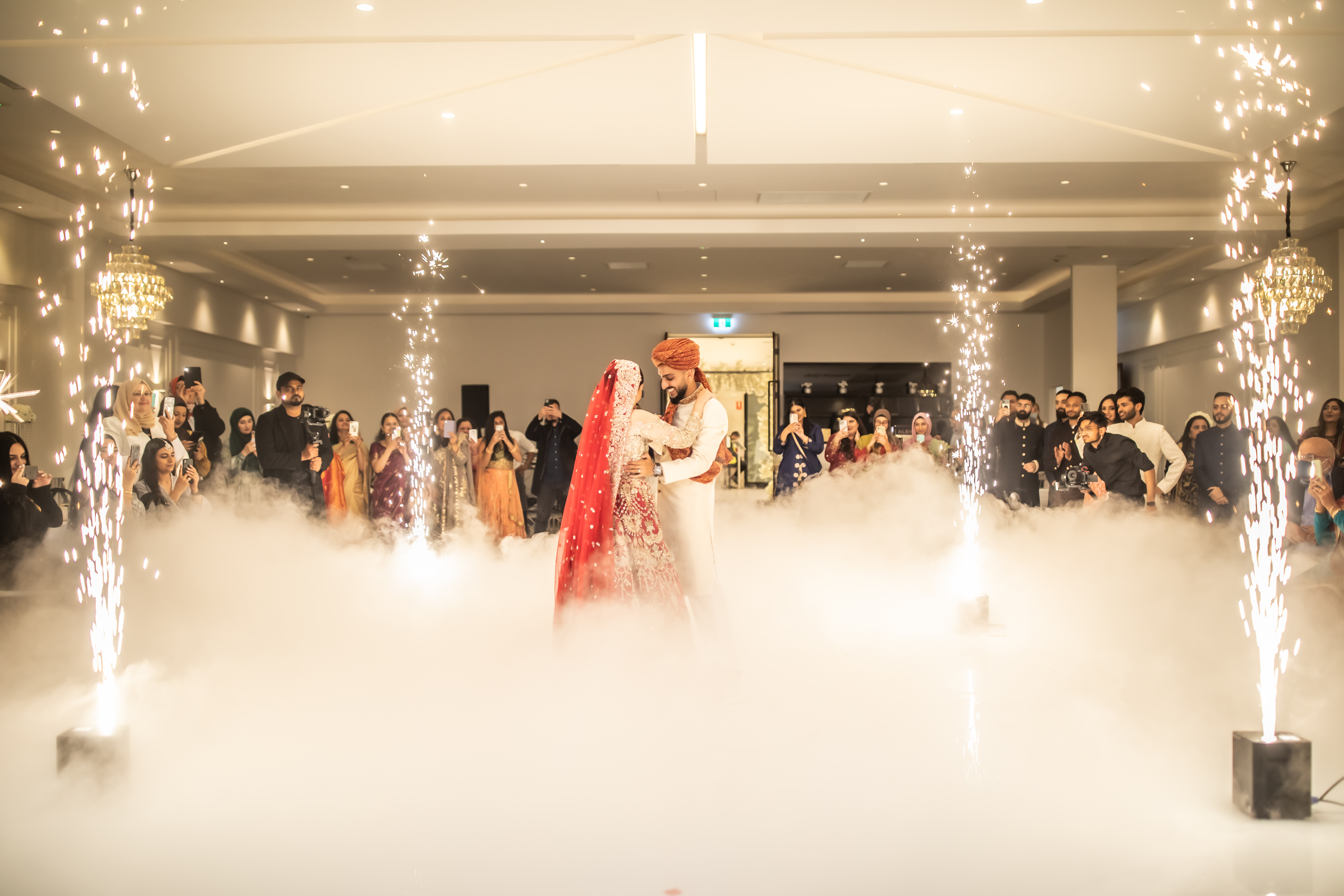 Couple sharing their first dance surrounded by cold sparks and low-lying dry ice clouds